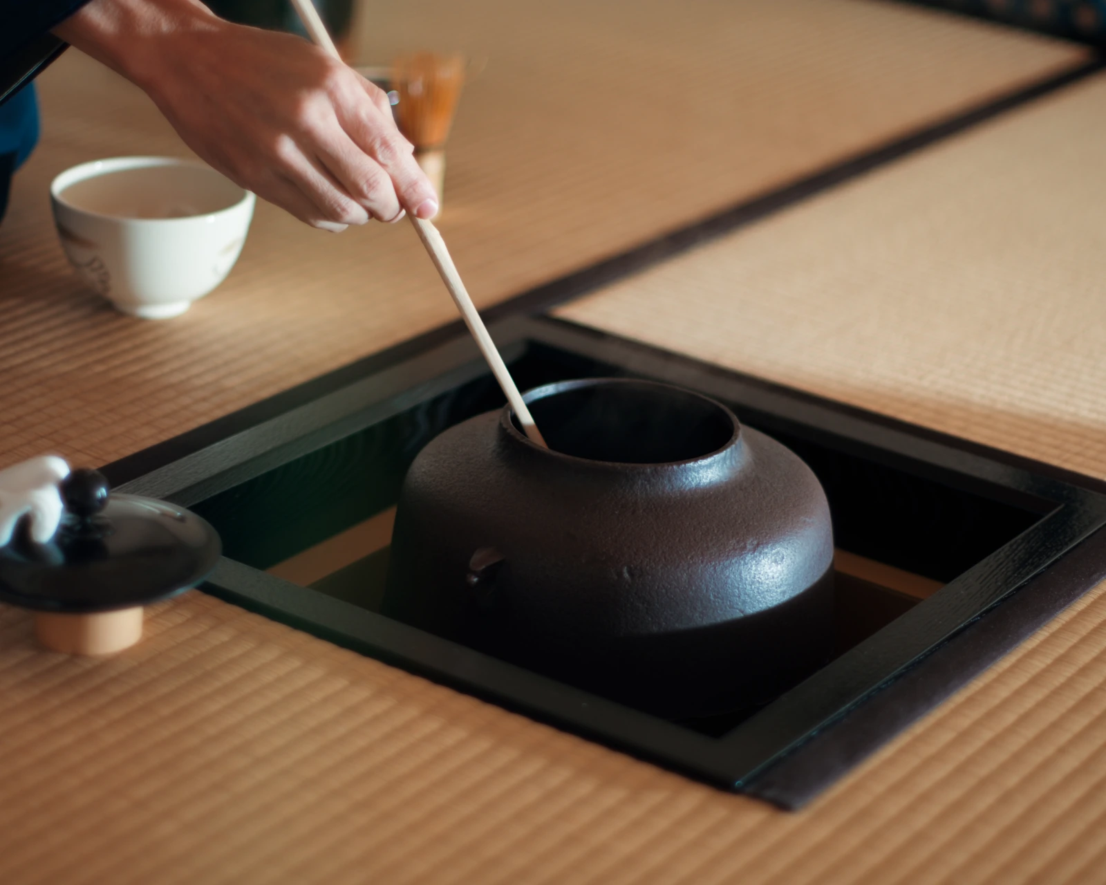 炉から柄杓で湯をくむ